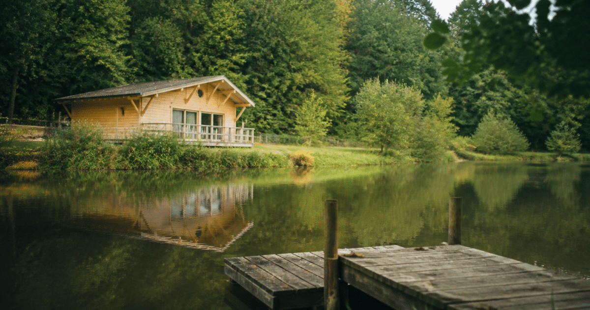 Maison en bois face a etang calme avec ponton de peche
