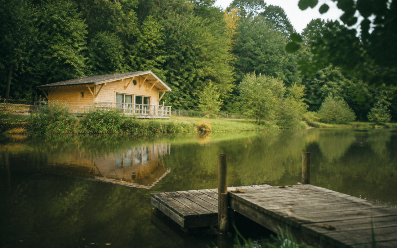 Maison en bois face a etang calme avec ponton de peche