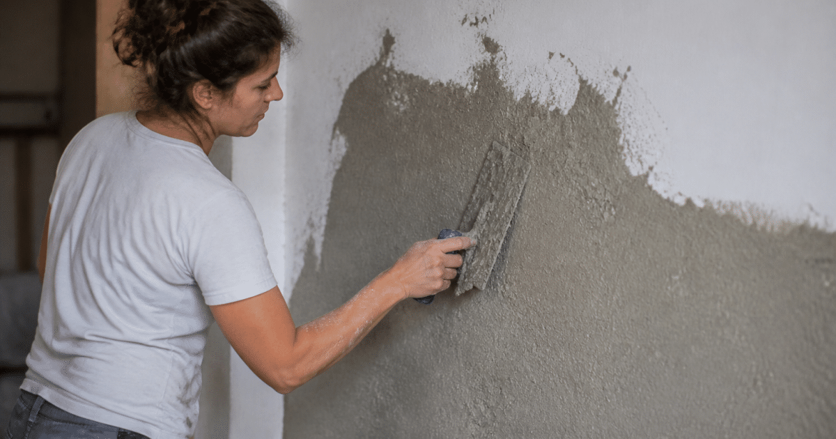 Applicateur étalant enduit chaux chanvre sur mur blanc