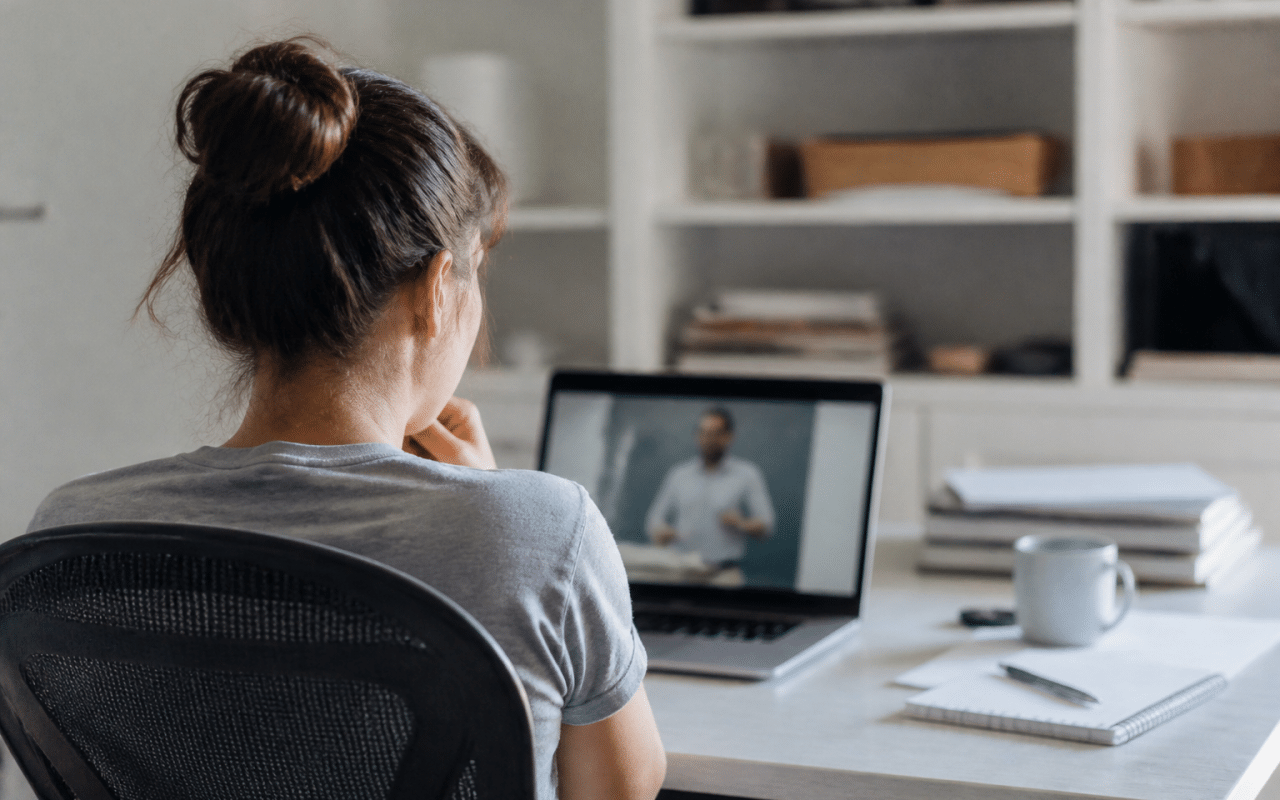 Personne assise à bureau suivant formation en ligne sur écran