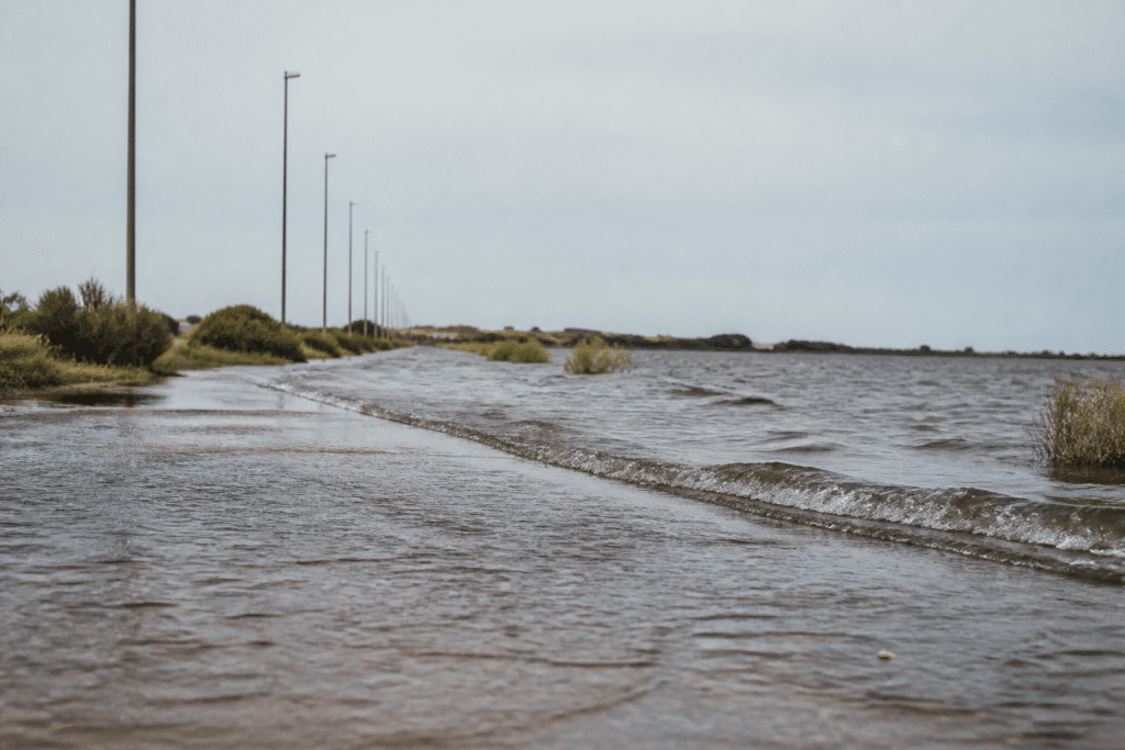 Eau montante inondant route côtière avec étang arrière-plan