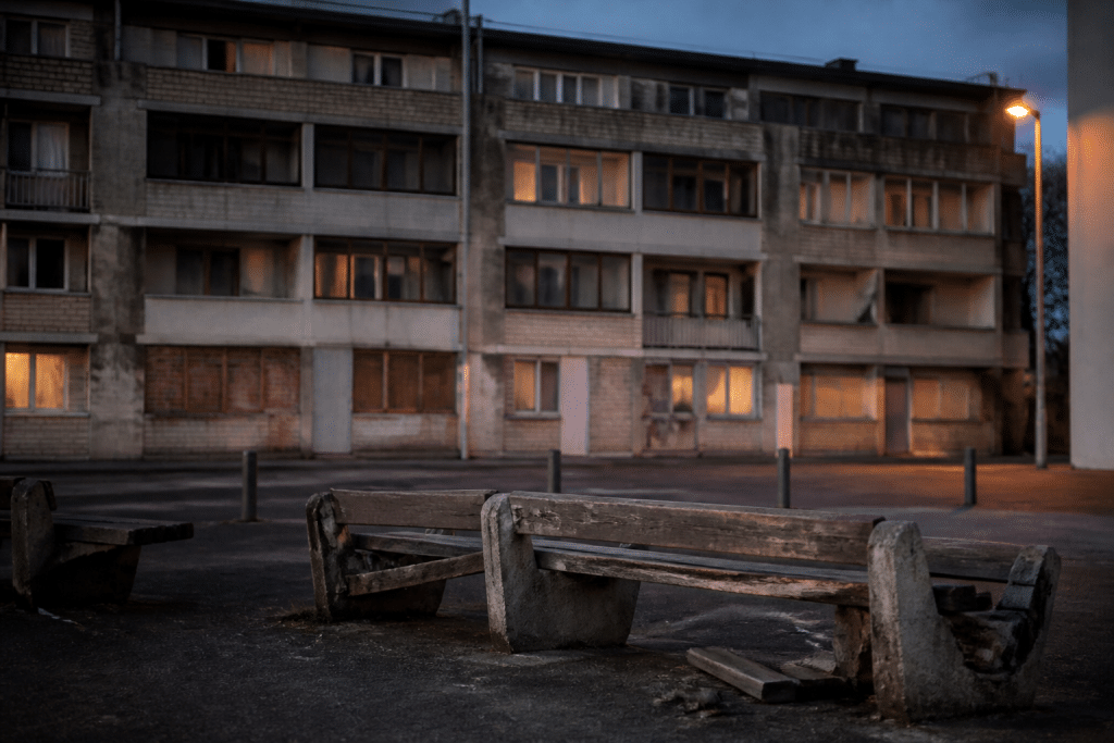 Immeuble urbain degradé avec bancs cassés en soirée