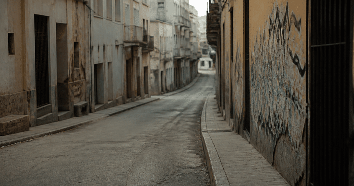 Rue urbaine déserte avec immeubles dégradés et graffitis visibles
